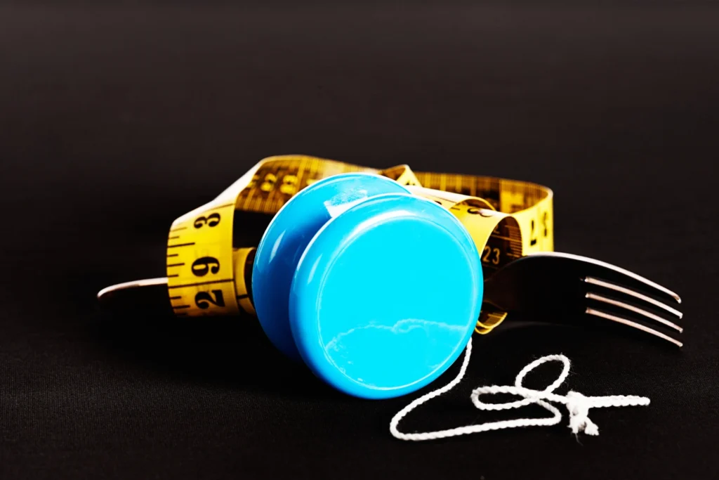 a yo-yo with a measuring cup and a fork, symbolizing the yo-yo effect after weight loss