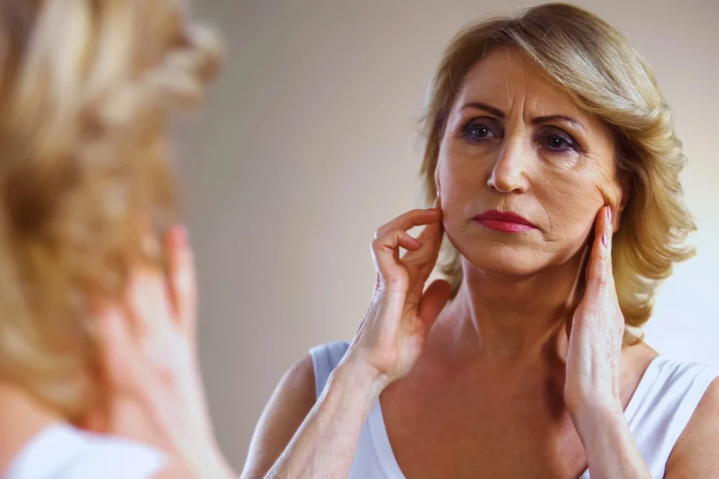 A woman looks at her face in the mirror